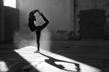 Ballerina dancing in an abandoned building on a sunny day in black and white - obrazy, fototapety, plakaty