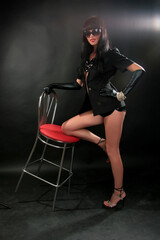 Portrait of a beautiful fashion girl brunette in the studio in blackleather  suit retro 90s vintage...