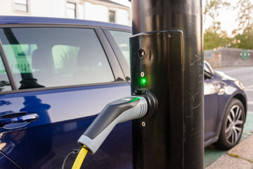 Electric car being charged from a charging point on a street light post.