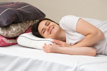 A woman sleeps on an orthopedic pillow made of memory foam, choosing it instead of other pillows made of fluff and sintepon