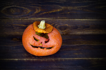 Stale halloween pumpkin on brown wooden surface, jack o lantern face wilted