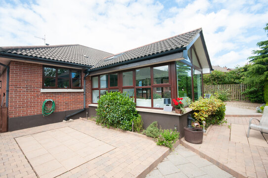 Sunroom extension on a modern bungalow with a low maintenance patio rear garden.
