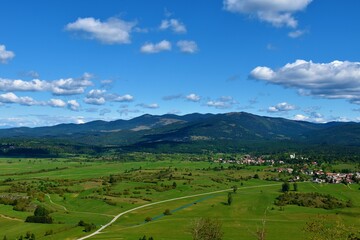 View of forest covered Javorniki mountains and green fields and a village bellow in Notranjska, Slovenia