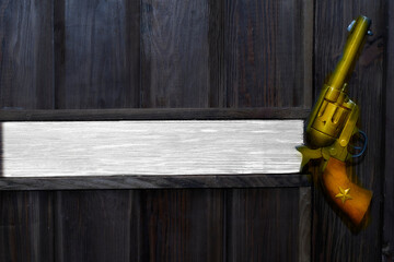 Cowboy gold gun revolver on a wooden black wall. Space for text. Boss's office