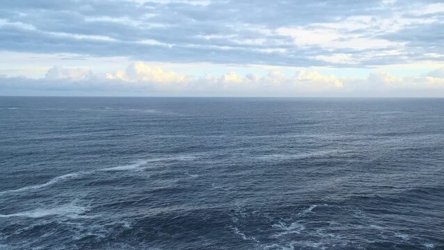 Panorama shot of the blue Cantabrian sea flowing in one direction on a cloudy day