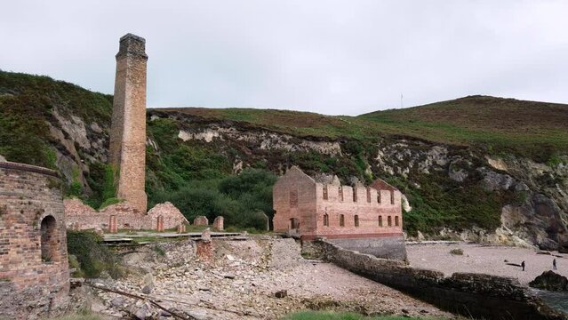 Porth Wen left pan across abandoned Victorian industrial brickwork factory remains on Anglesey eroded coastline