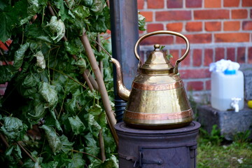 A close up on an ancient kettle made out of iron, steel, or brass standing on a temporary grill or...