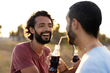 Gay couple embracing and showing their love. Young men drinking juice..