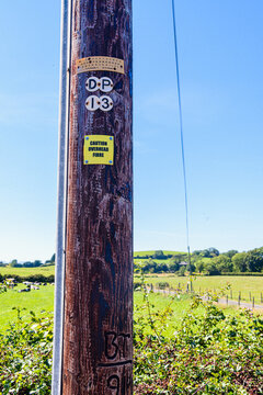 Sign on a wooden telephone pole warning people that the pole is carrying fibre optic cable.