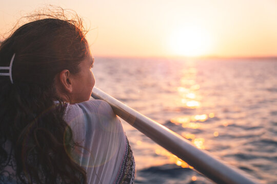 A woman enjoys watching the sunset from a boat