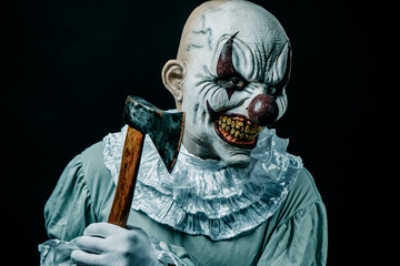 creepy evil clown threatening with an axe