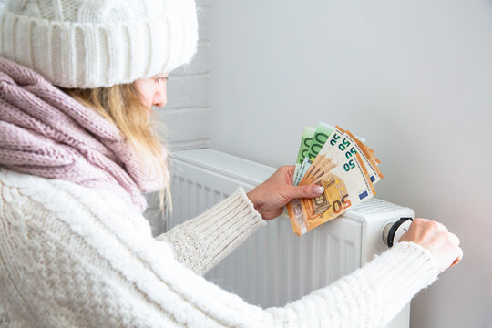 Saving home heating, expensive payment for heating. Radiator and euro money banknotes in woman hands. Expensive utility bills.