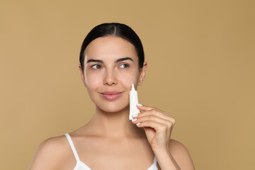 Beautiful young woman with gel on skin under eye against beige background. Space for text