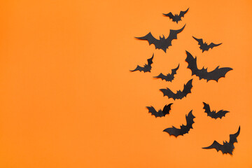 Paper bats and space for text on orange background, flat lay. Halloween decor