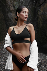 Beautiful young woman in stylish bikini near waterfall outdoors