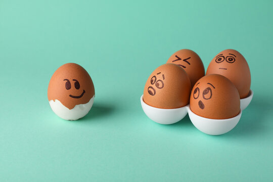 Eggs with drawn faces on turquoise background. Exhibitionist concept