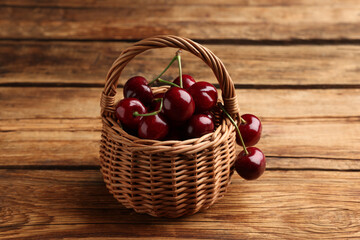Fototapeta na wymiar Wicker basket of ripe sweet cherries on wooden table