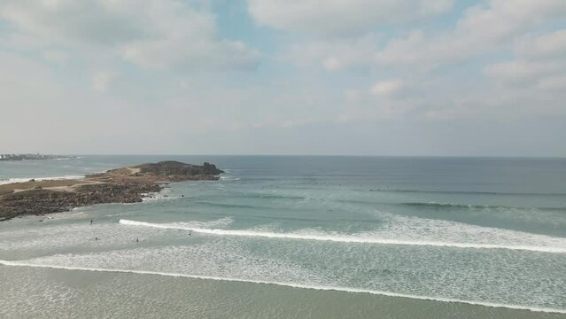Surfers surf on waves with surfboards at the Pointe de la Torche in Brittany