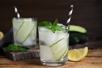 Glasses of refreshing cucumber water with mint on wooden table