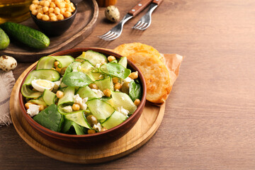 Delicious cucumber salad and rosted bread served on wooden table. Space for text