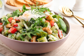 Bowl of delicious cucumber salad served on white table, closeup