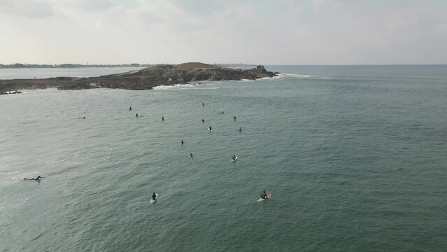 Surfers surf on waves with surfboards at the Pointe de la Torche in Brittany