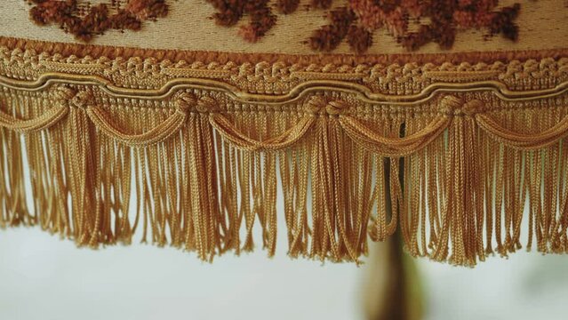 Close-up vintage style floor lamp torchere with bell shape fringed drapery shade being switched on and off by pulling a chain, slow motion.