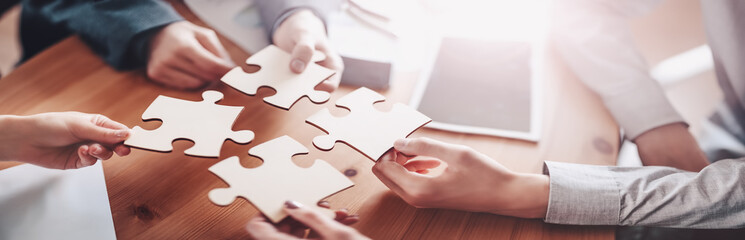 Buisnesswomen and buisnessmen working together while putting together puzzles.
