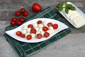 Naklejka na ściany i meble Tomatoes with mozzarella balls on a plate.