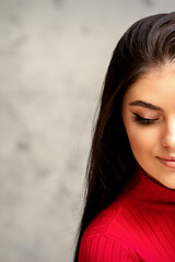 Naklejka premium The fashionable young woman. Portrait of the beautiful female model with long hair and makeup with eyelash extensions. Beauty young woman with a black hairstyle on the background of a gray wall