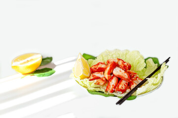 Seafood salad with juicy crab meat, fresh iceberg lettuce leaves and lemon on a white plate