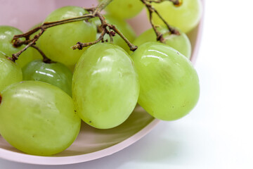 
closeup bunch of green grapes in a pink bowl (diet or healthy food concept)