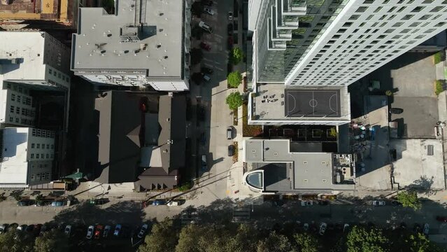 Top down aerial shot of an urban block with empty streets and a rooftop basketball court.
