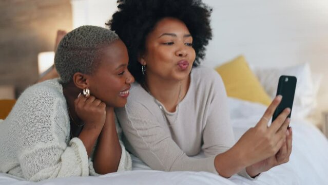 Happy, friends and selfie with phone in bed with a smile, relax and funny during a luxury vacation in a hotel room. African american women having fun with social media post on a 5g mobile smartphone