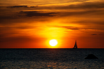 Sunset over the sea with a sailing ship on the horizon