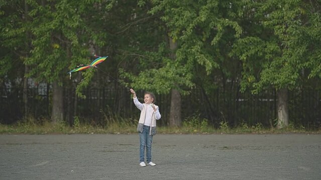 a child in a vest launches a kite in the park