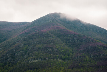 Imposing mass of Oribio peak with its cliffs populated with purple heather and birch forests