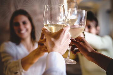 Cheerful women toasting together raising white wine glasses of wine