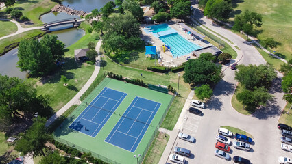 Aerial view large tennis court and swimming pool at community recreational center with trails and...