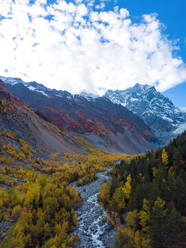Beautiful, delightful autumn view from a drone of the mountains, the river, the Chalaadi glacier on a sunny day. Very beautiful autumn landscape of the mountains. Vertical photo