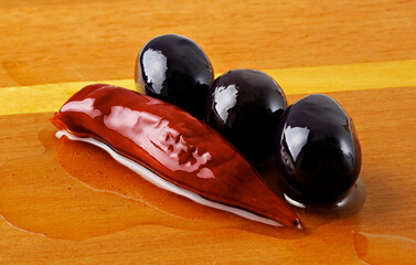 Azeitona preta com pimenta em fundo de madeira