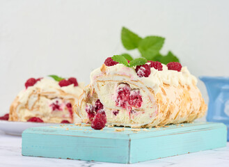 Baked meringue roll with cream and fresh red raspberry, white background.