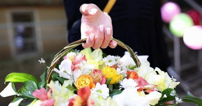Woman holds beautiful gift paper basket with flowers in hands