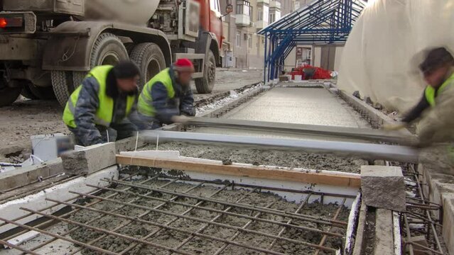 Pouring ready-mixed concrete after placing steel grid reinforcement to make the road by concrete mixer timelapse hyperlapse. Reconstruction of tram tracks on a city street