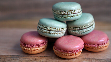 Fototapeta premium Green and pink macarons stacked up on a wooden background 