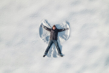 Man lying on a snow and doing angel print on a snow covered land. Aerial, top view. Drone photo. Winter - 532738442