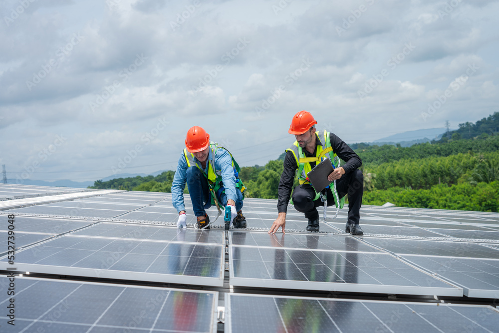 Poster professional worker using drill installing solar panels on the roof of a factory,alternative energy 