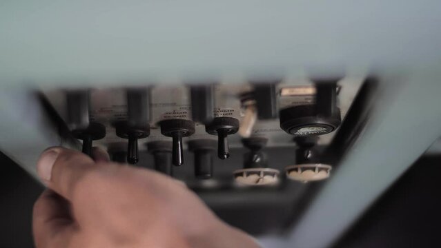 Man switches a lot of toggle switches on the dashboard of a diesel railroad locomotive. Close-up 