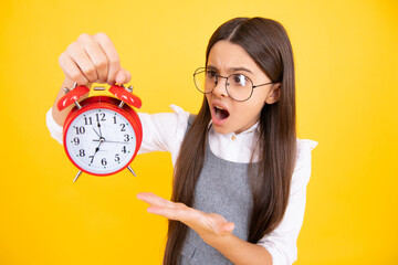 Child teenager girl with alrm clock isolated on yellow background. Time and deadline concept. Angry...