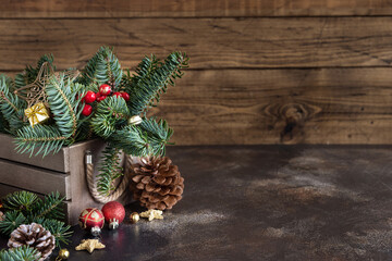 Box with Christmas decorations, pine cones and green fir branches close up on wooden table